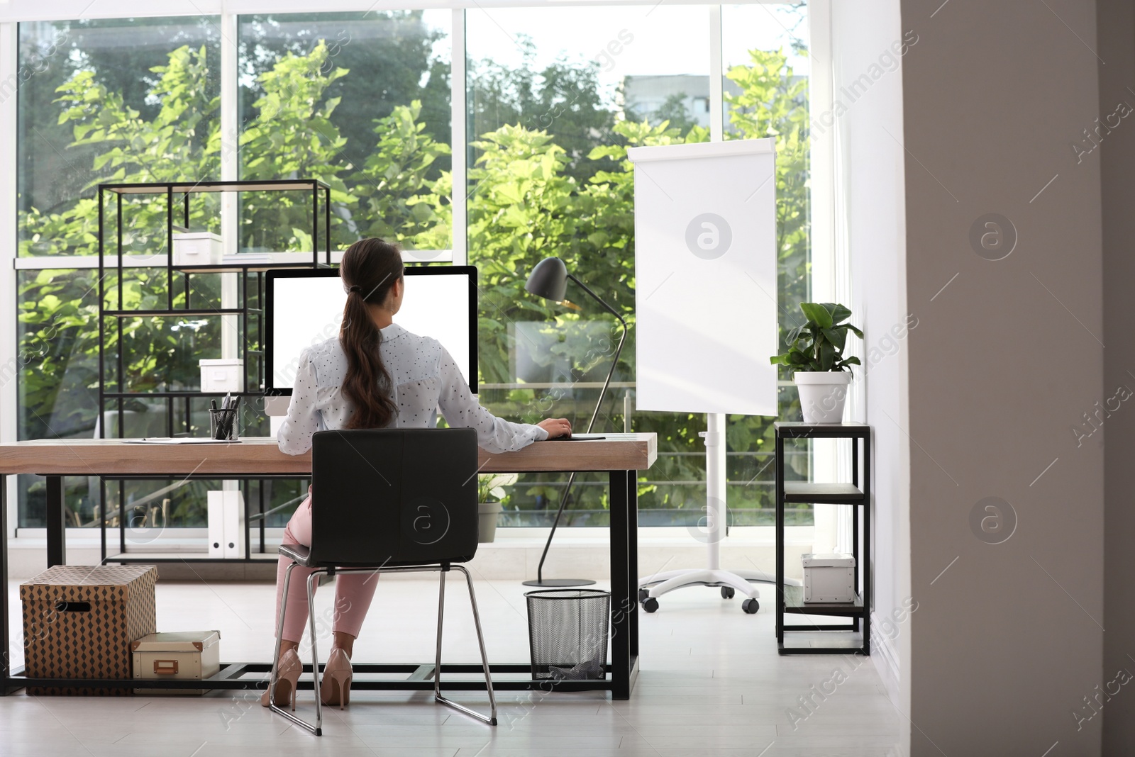 Photo of Young woman working at table in modern office