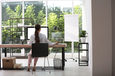 Young woman working at table in modern office