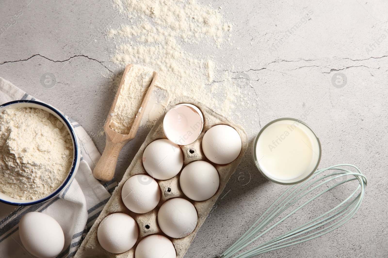 Photo of Making dough. Flour, eggs, milk and tools on light textured table, flat lay