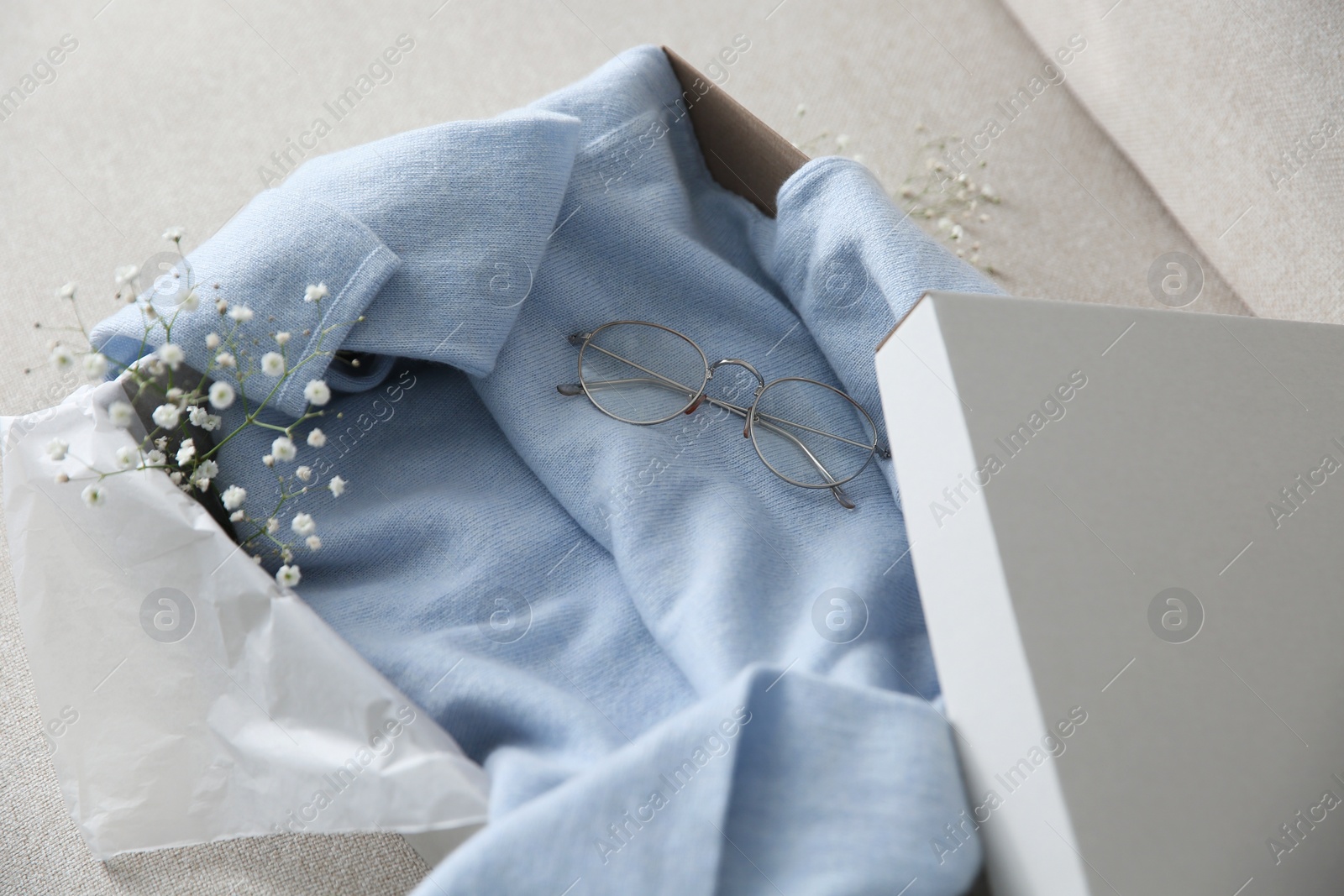 Photo of Soft cashmere sweater in box on sofa, closeup