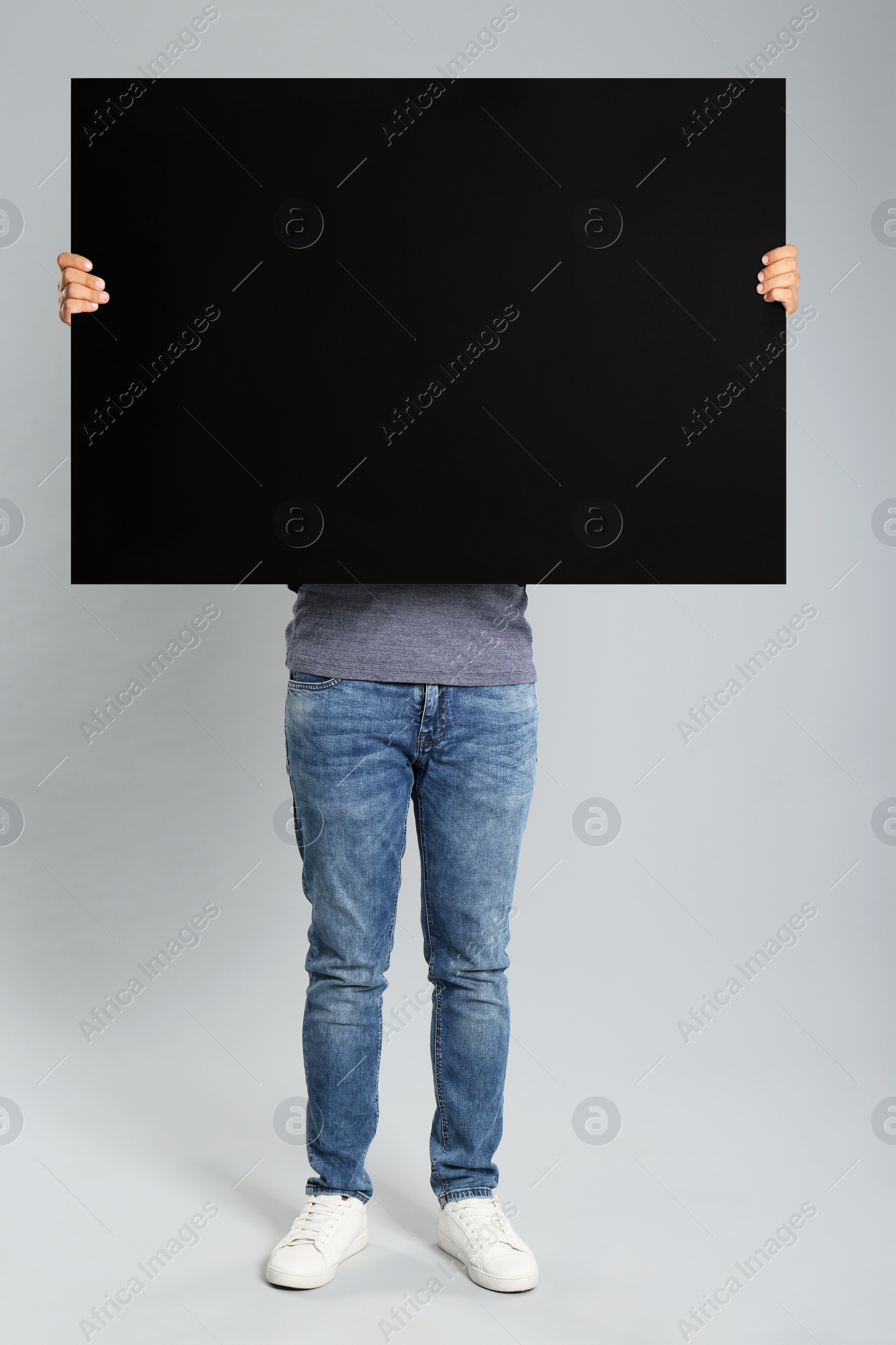 Photo of Man holding black blank poster on grey background. Mockup for design