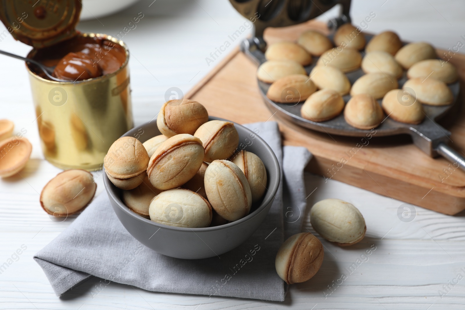 Photo of Delicious walnut shaped cookies with condensed milk on white wooden table, closeup