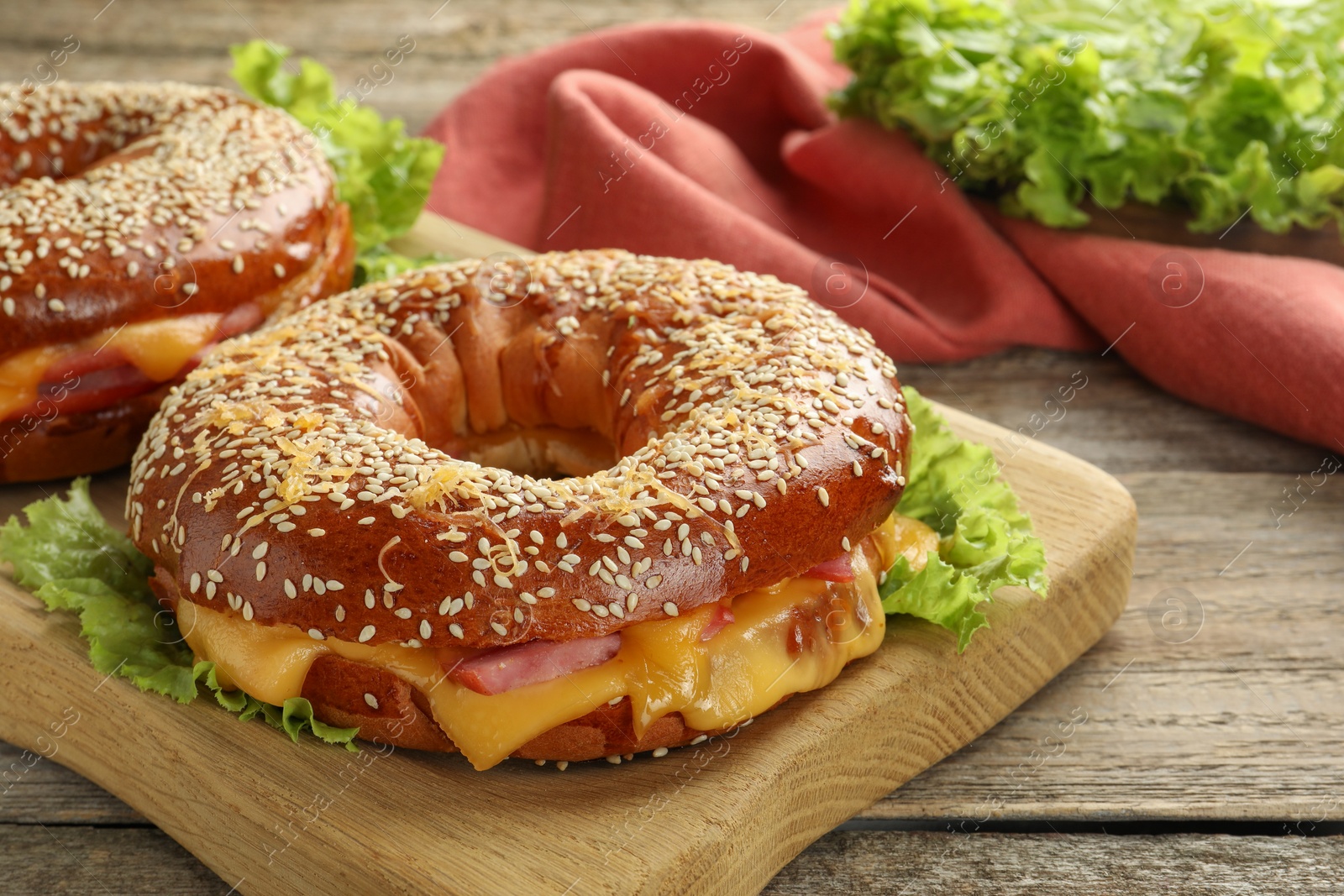 Photo of Delicious bagels with ham and cheese on wooden table