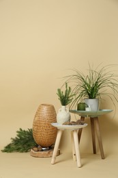 Decorative tables with candles and plants on beige background