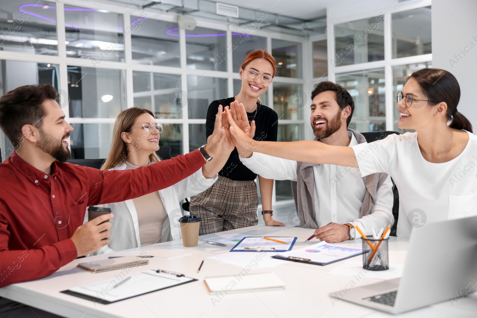 Photo of Team of employees joining hands in office