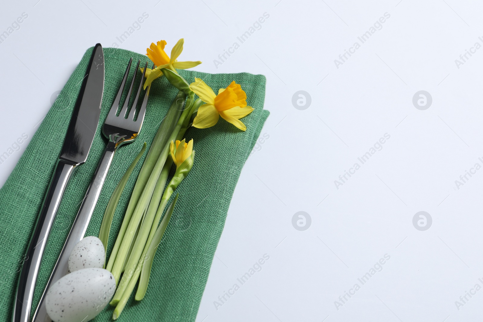 Photo of Cutlery set, Easter eggs and narcissuses on white background, space for text. Festive table setting