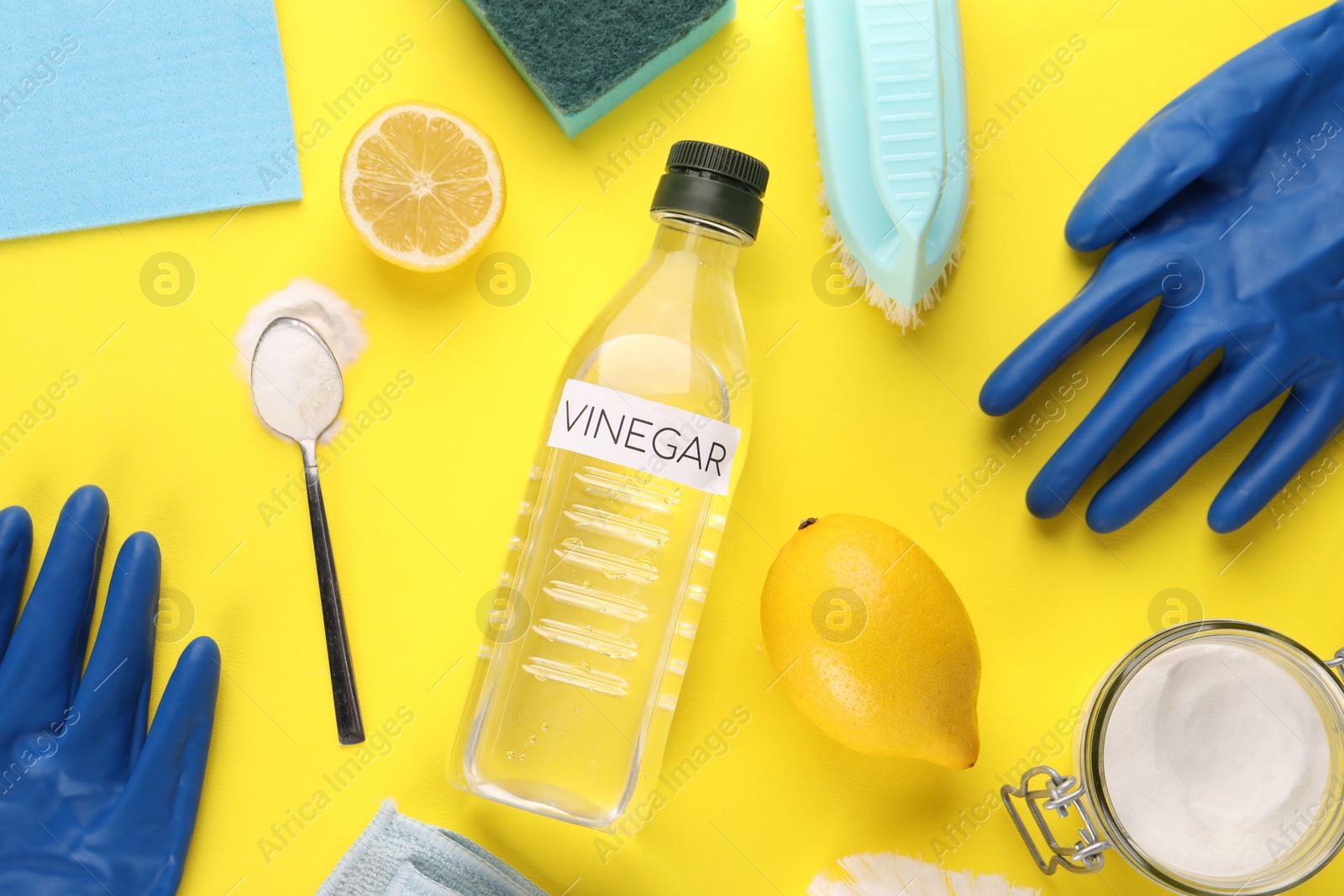 Photo of Eco friendly natural cleaners. Flat lay composition with bottle of vinegar on yellow background