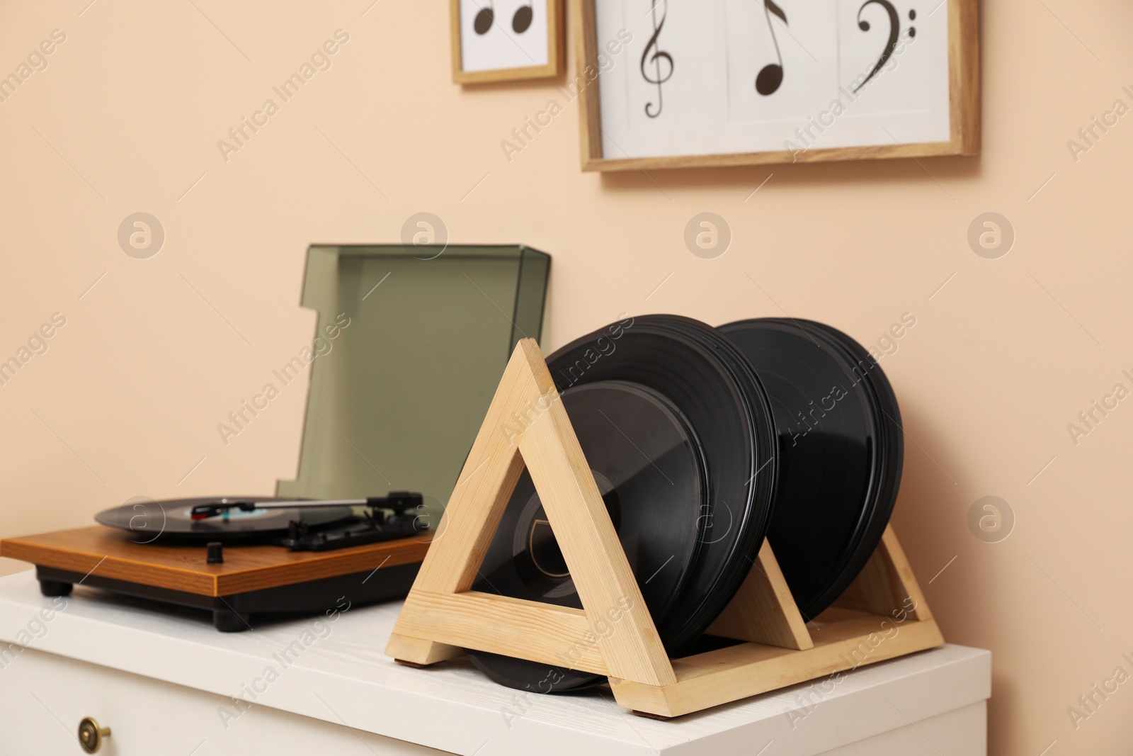 Photo of Vinyl records and player on white wooden drawer dresser near beige wall