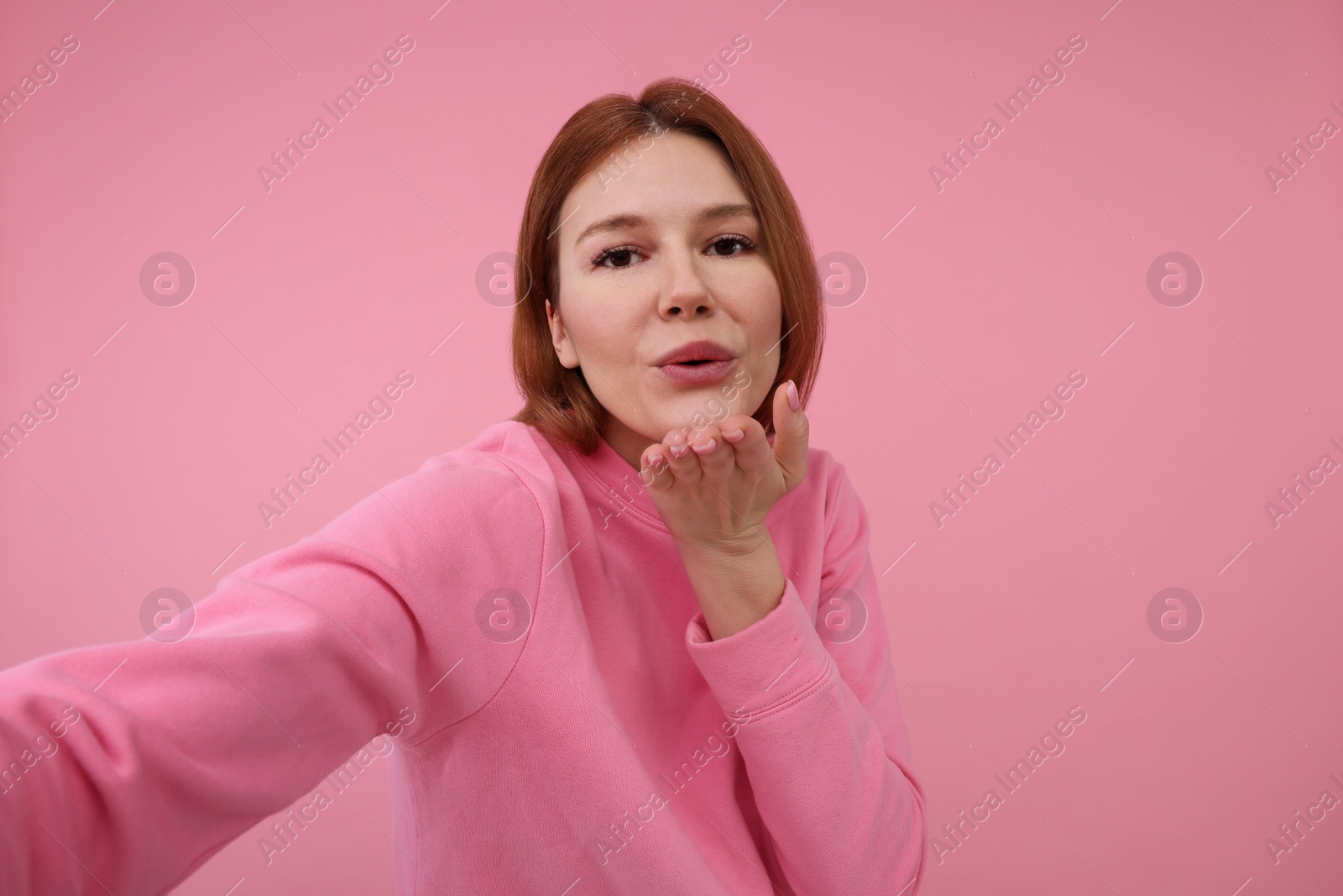 Photo of Beautiful woman taking selfie on pink background