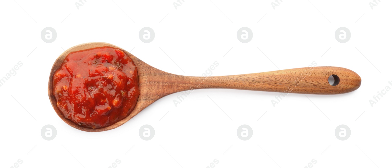 Photo of Delicious adjika sauce in wooden spoon isolated on white, top view