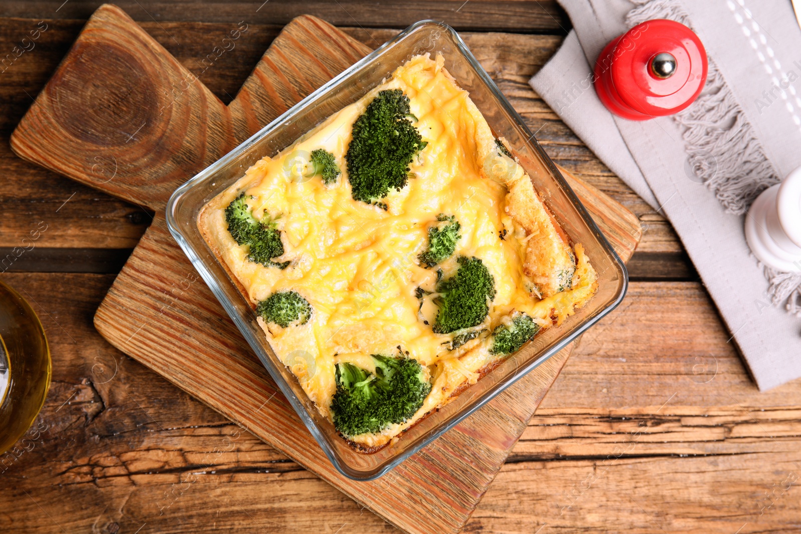 Photo of Tasty broccoli casserole in baking dish on wooden table, flat lay