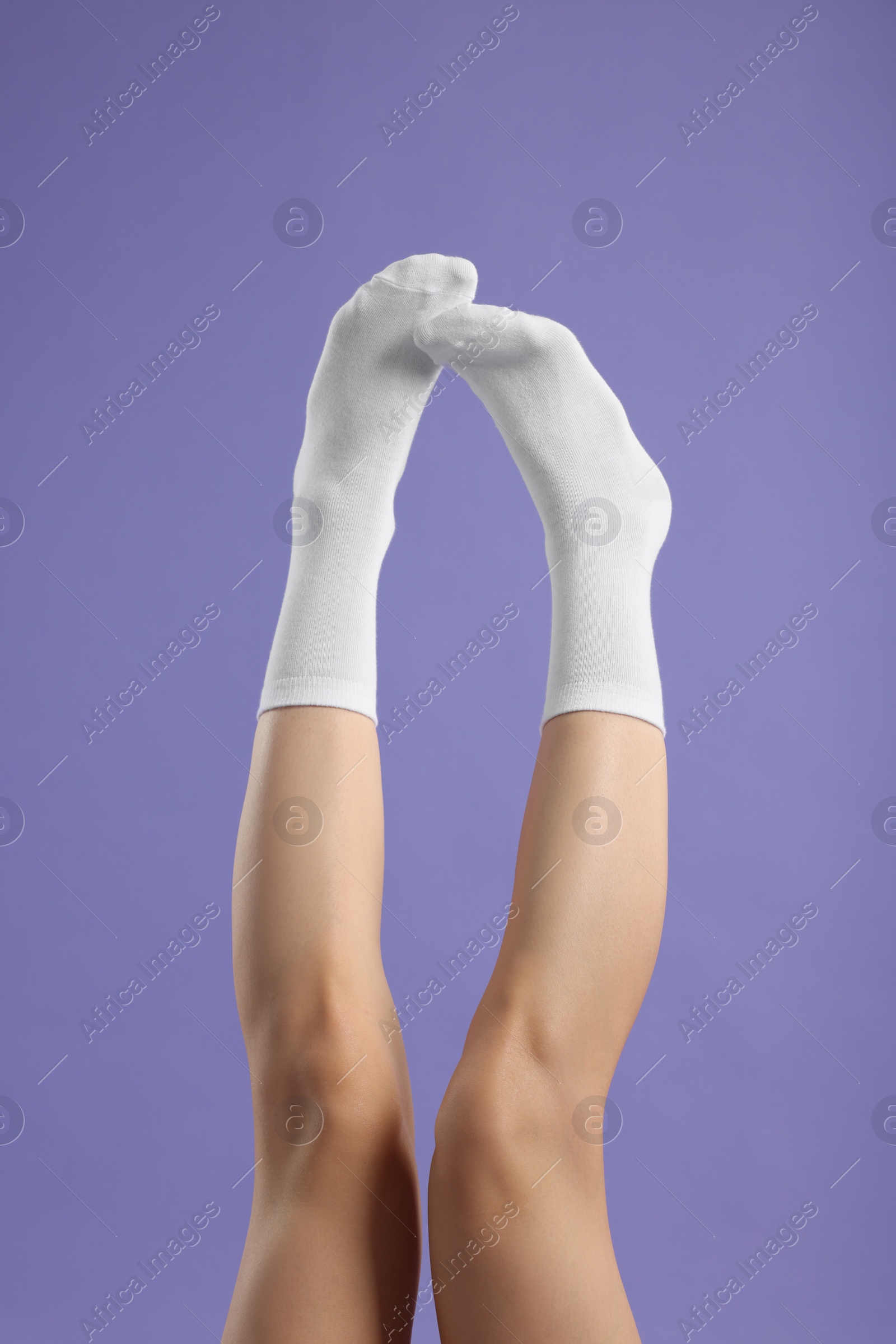 Photo of Woman in stylish white socks on violet background, closeup