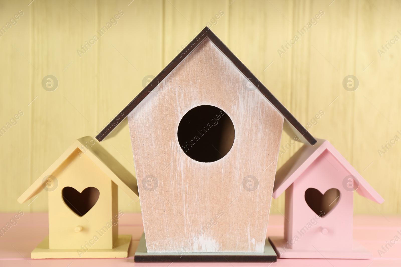 Photo of Beautiful bird houses on pink wooden table