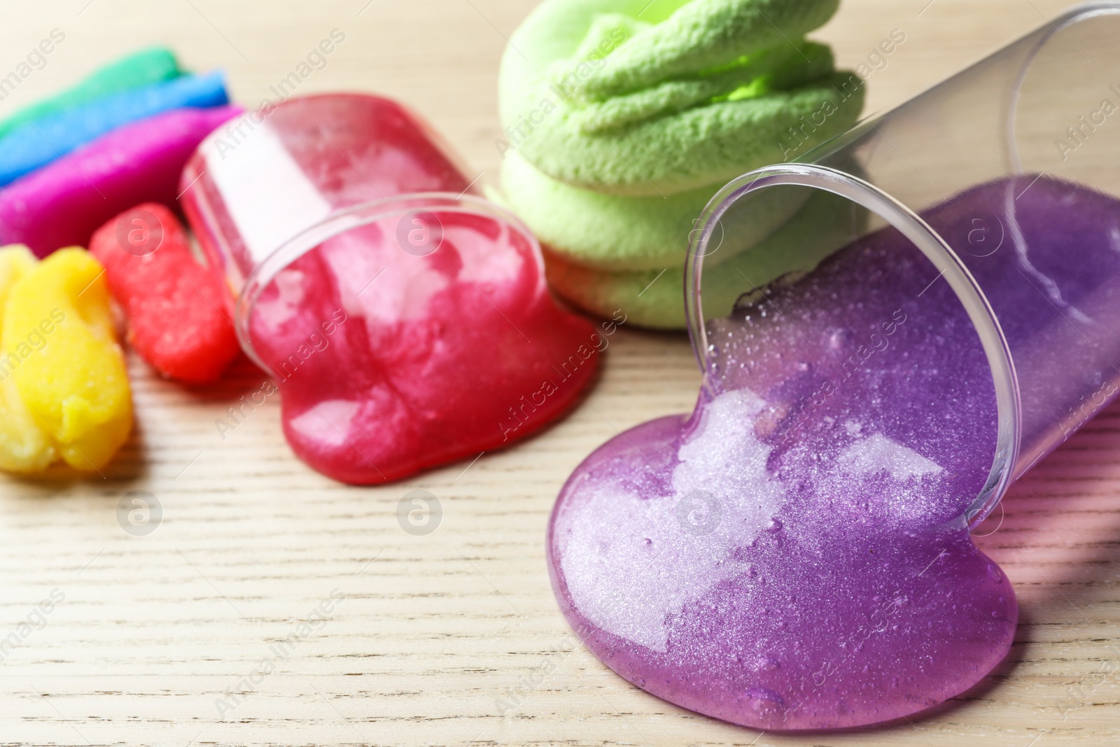 Photo of Different bright slimes on wooden background, closeup