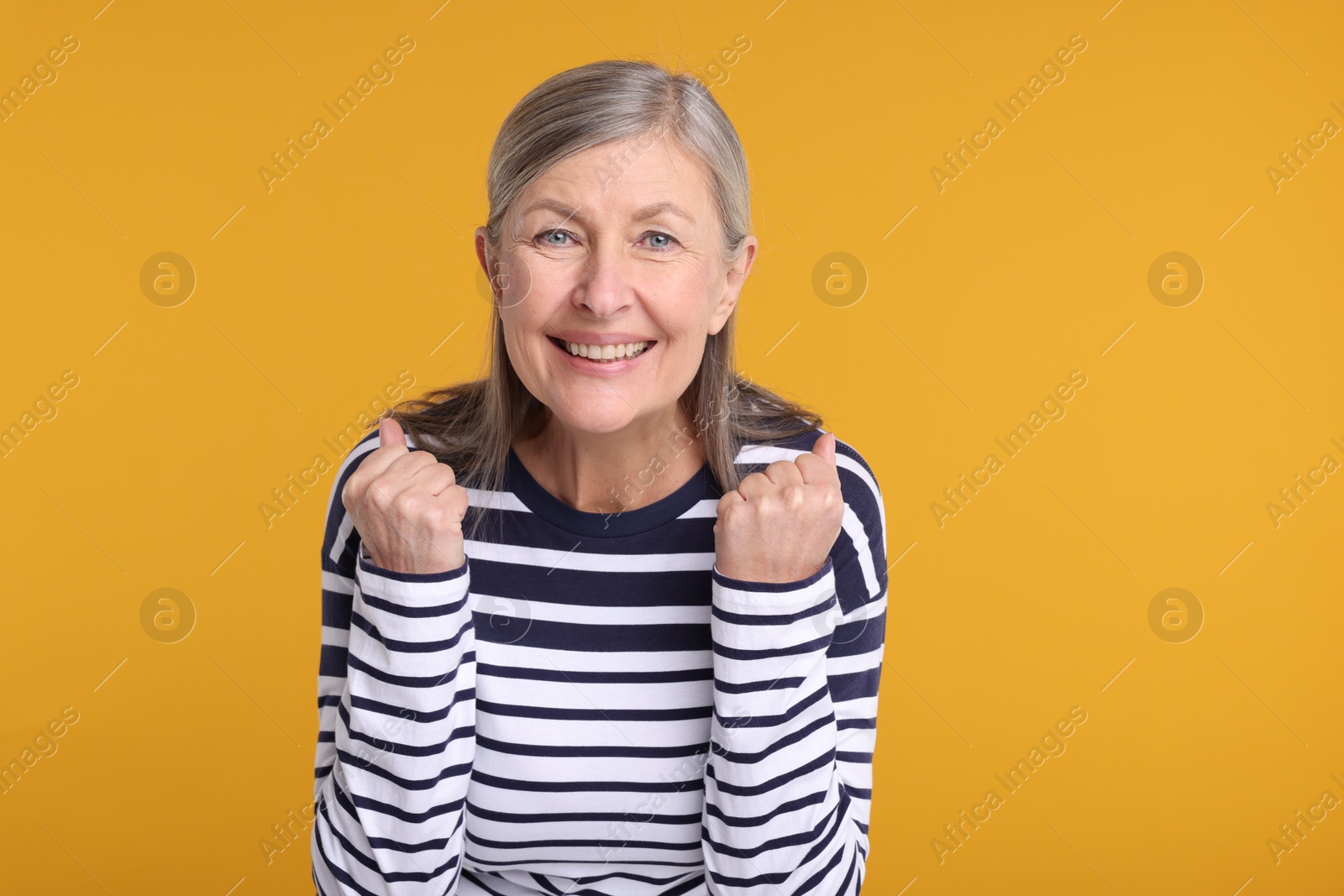 Photo of Portrait of happy surprised senior woman on yellow background, space for text