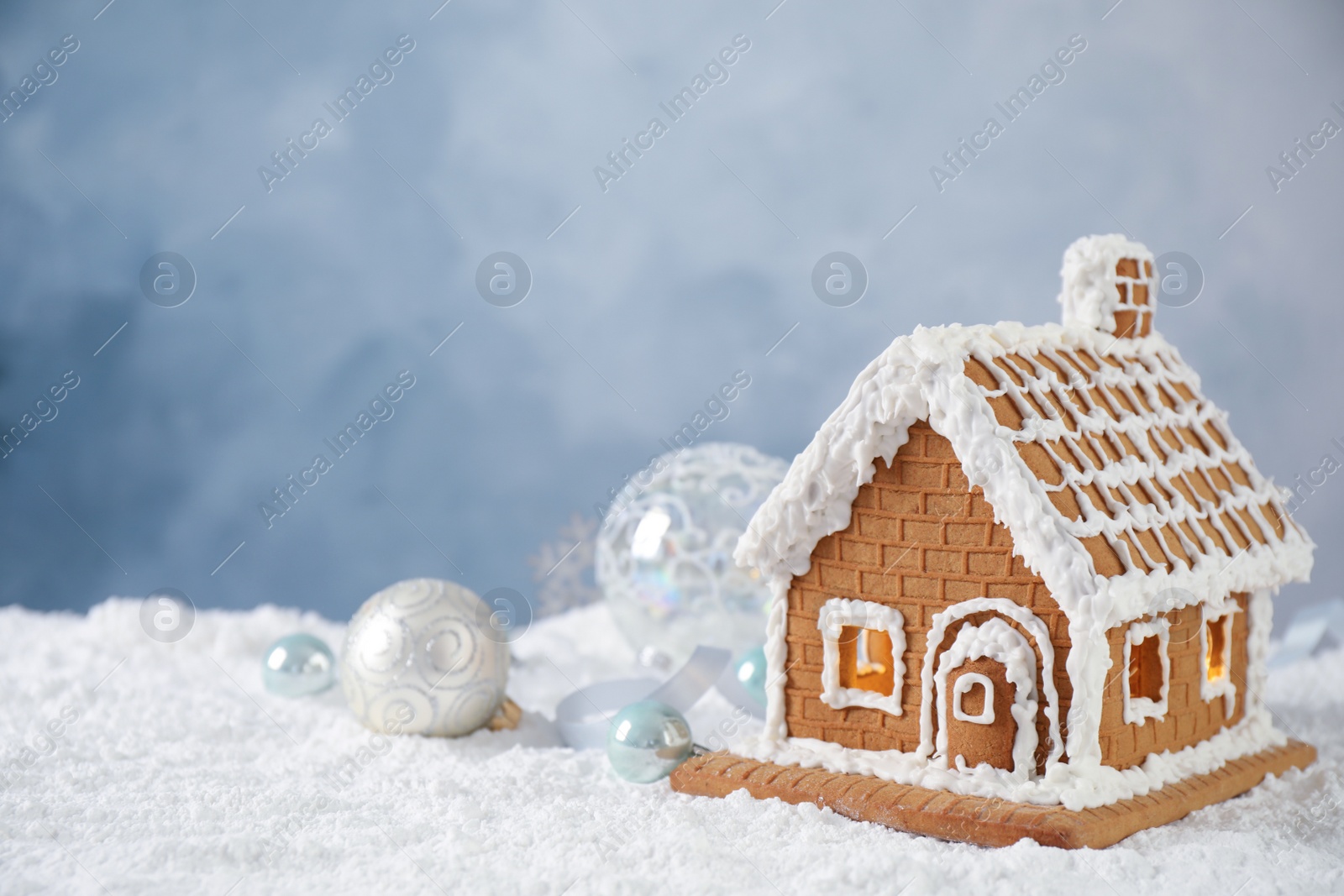 Photo of Beautiful gingerbread house decorated with icing on snow, space for text