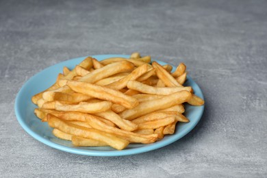 Photo of Turquoise plate with delicious french fries on light gray marble table, closeup
