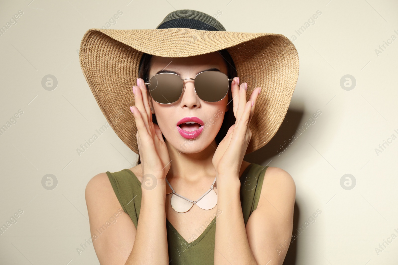 Photo of Emotional woman in stylish sunglasses and hat on beige background