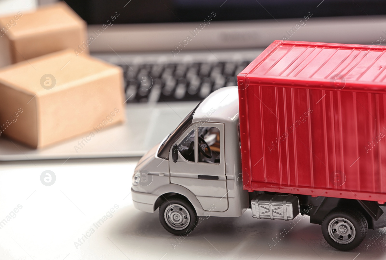 Photo of Toy truck near laptop on table. Logistics and wholesale concept