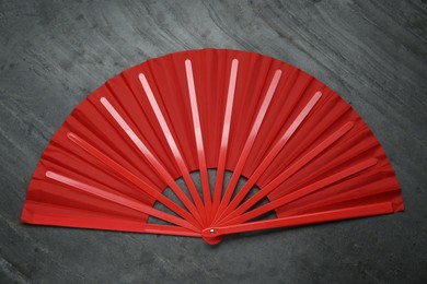 Bright red hand fan on grey background, top view