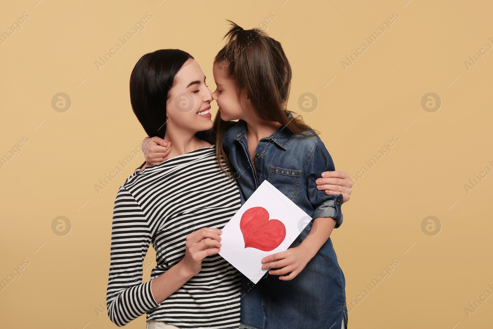 Photo of Happy woman with her cute daughter and handmade greeting card on beige background. Mother's day celebration