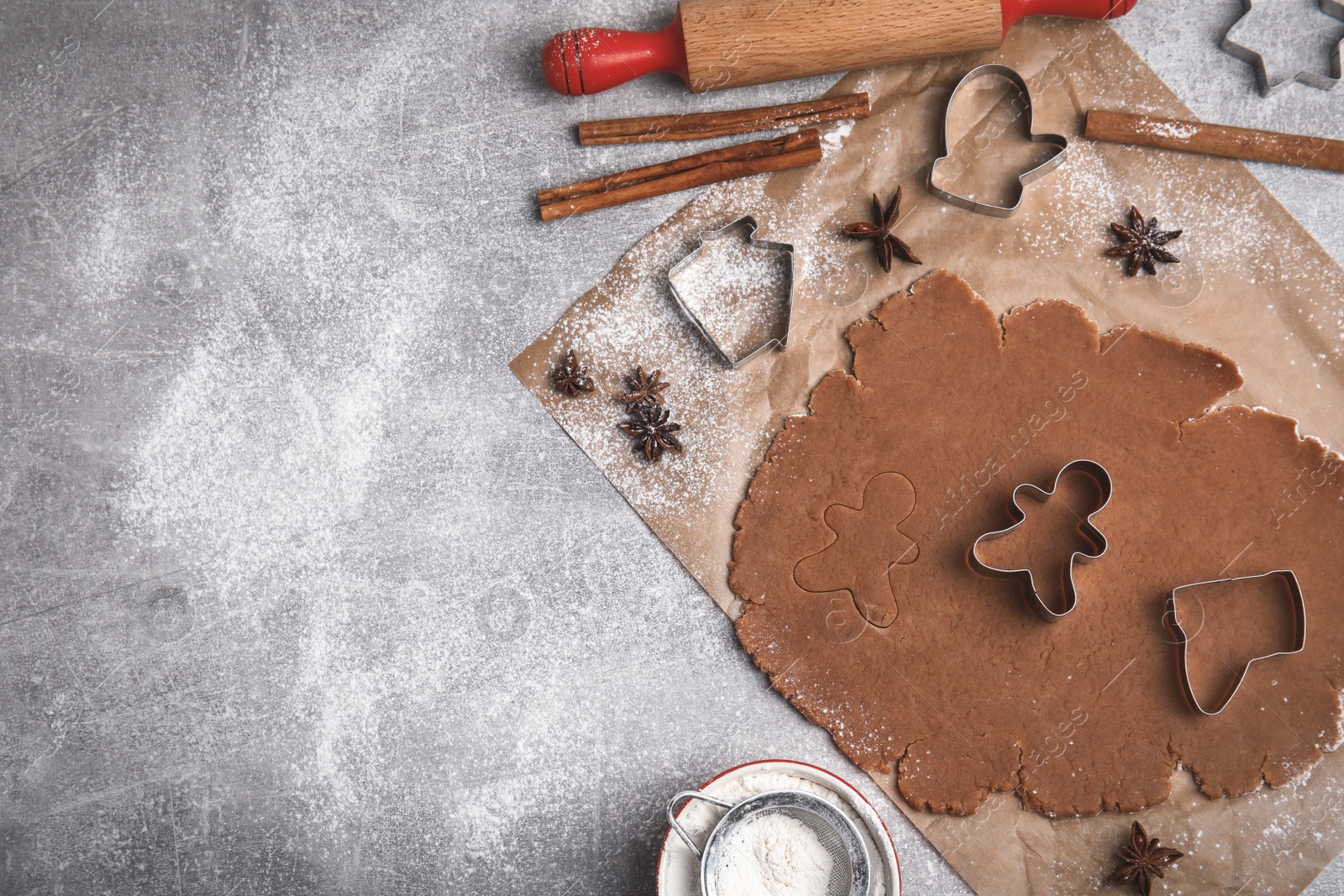 Photo of Making Christmas cookies. Flat lay composition with raw dough and cutters on grey table, space for text