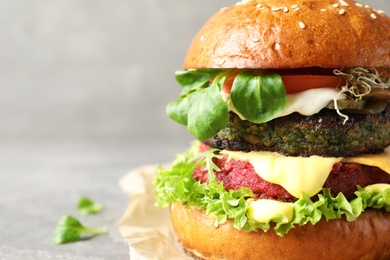 Photo of Vegan burger with beet and falafel patties on grey background, closeup