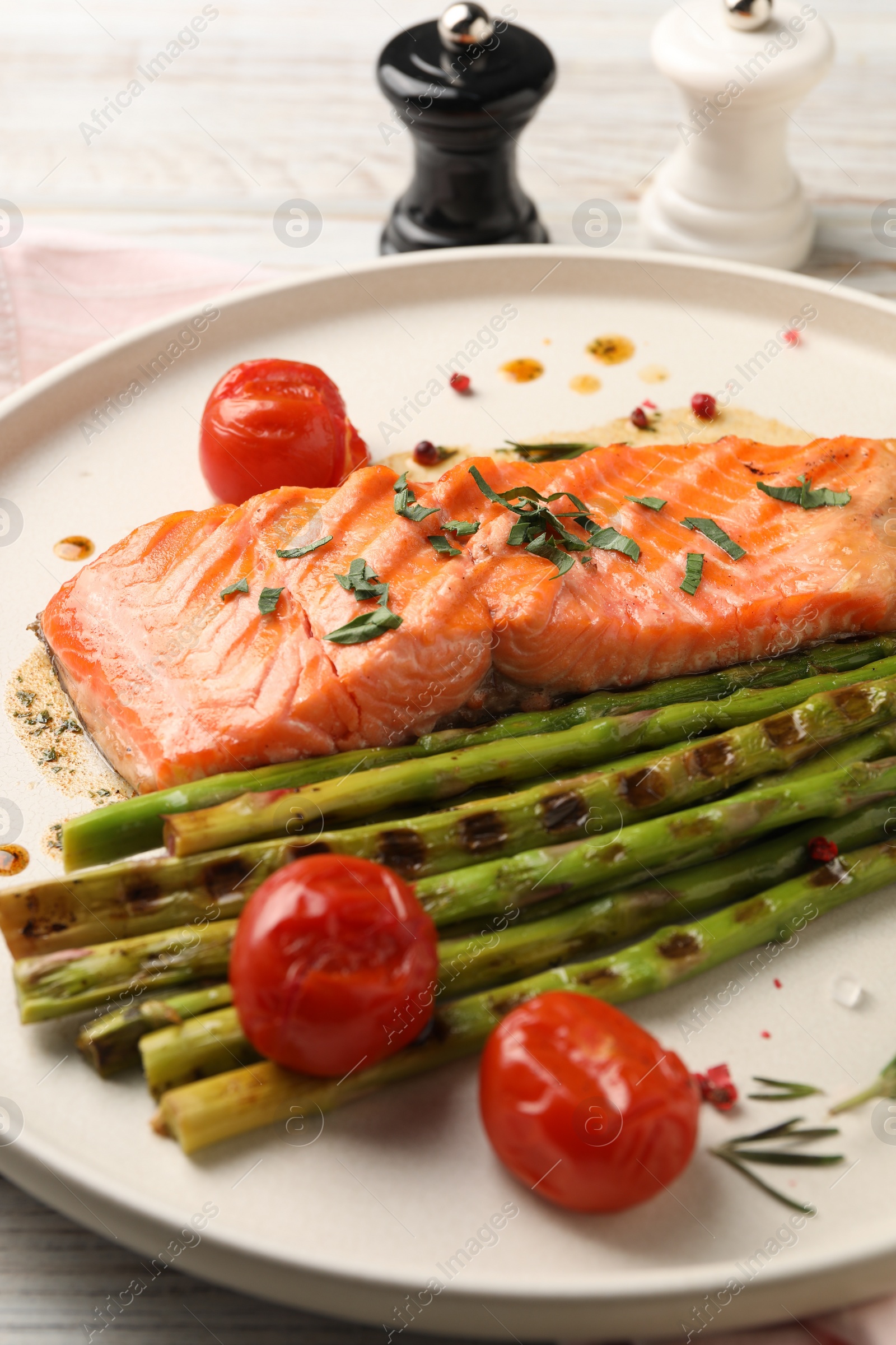 Photo of Tasty grilled salmon with tomatoes, asparagus and spices on table, closeup