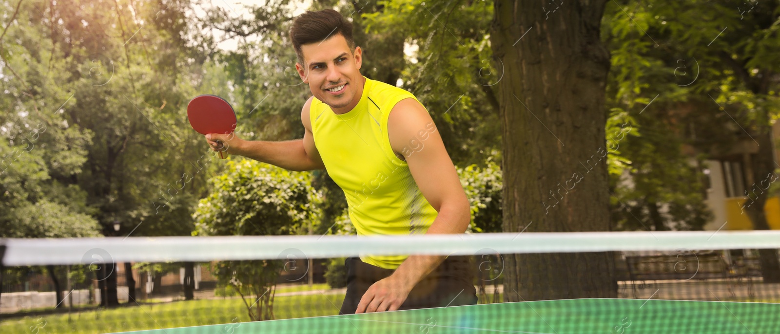 Image of Man playing ping pong in park on summer day. Banner design