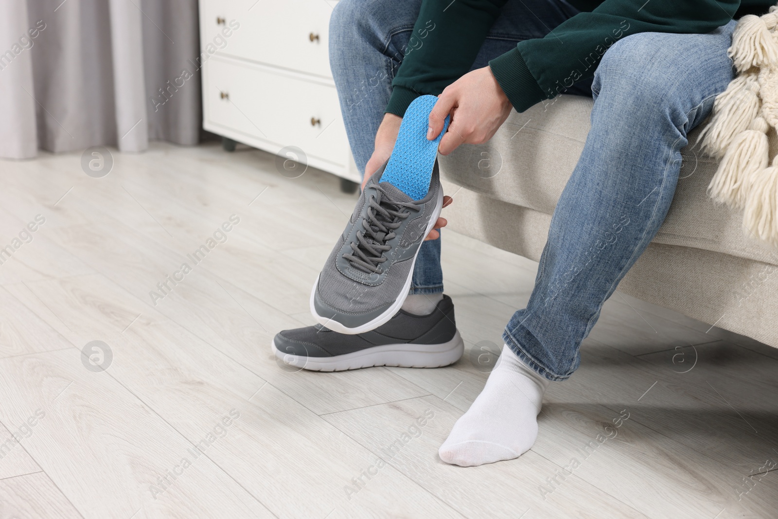 Photo of Man putting orthopedic insole into shoe indoors, closeup. Space for text