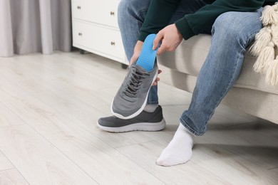 Photo of Man putting orthopedic insole into shoe indoors, closeup. Space for text