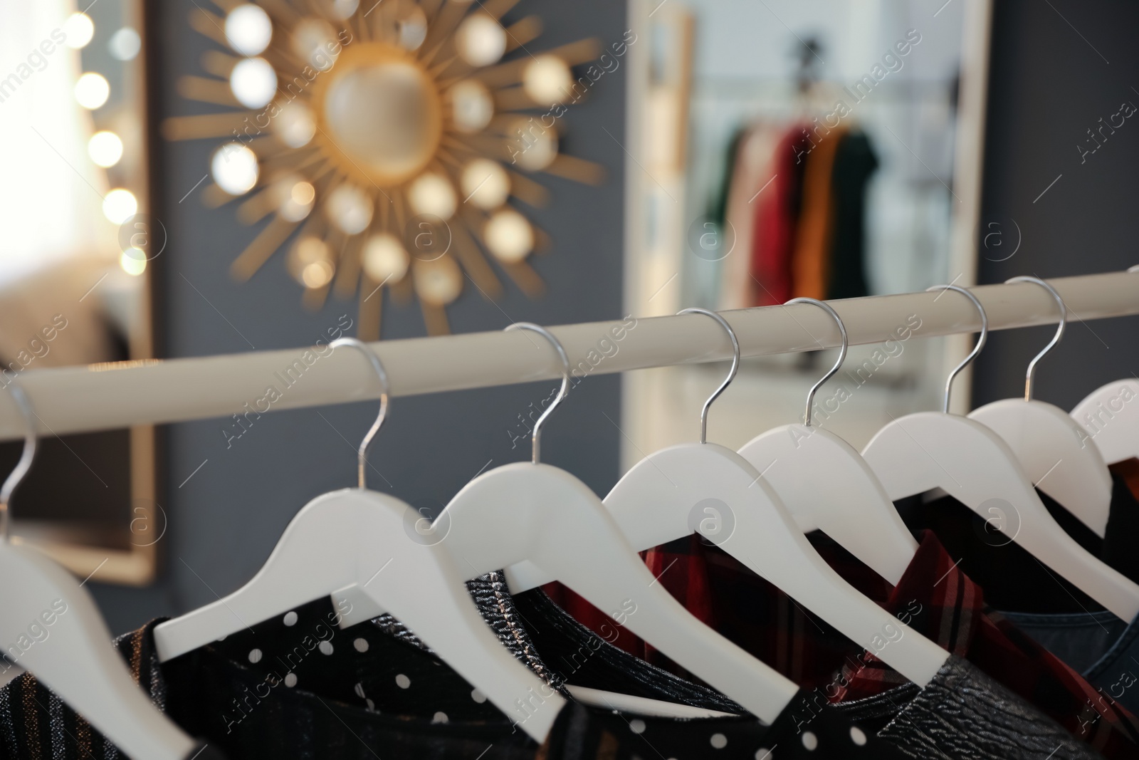 Photo of Collection of modern clothes hanging on rack indoors