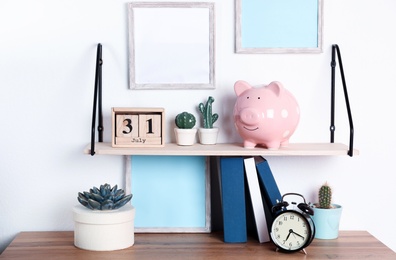 Photo of Color piggy bank on shelf over table in room. Cute interior element