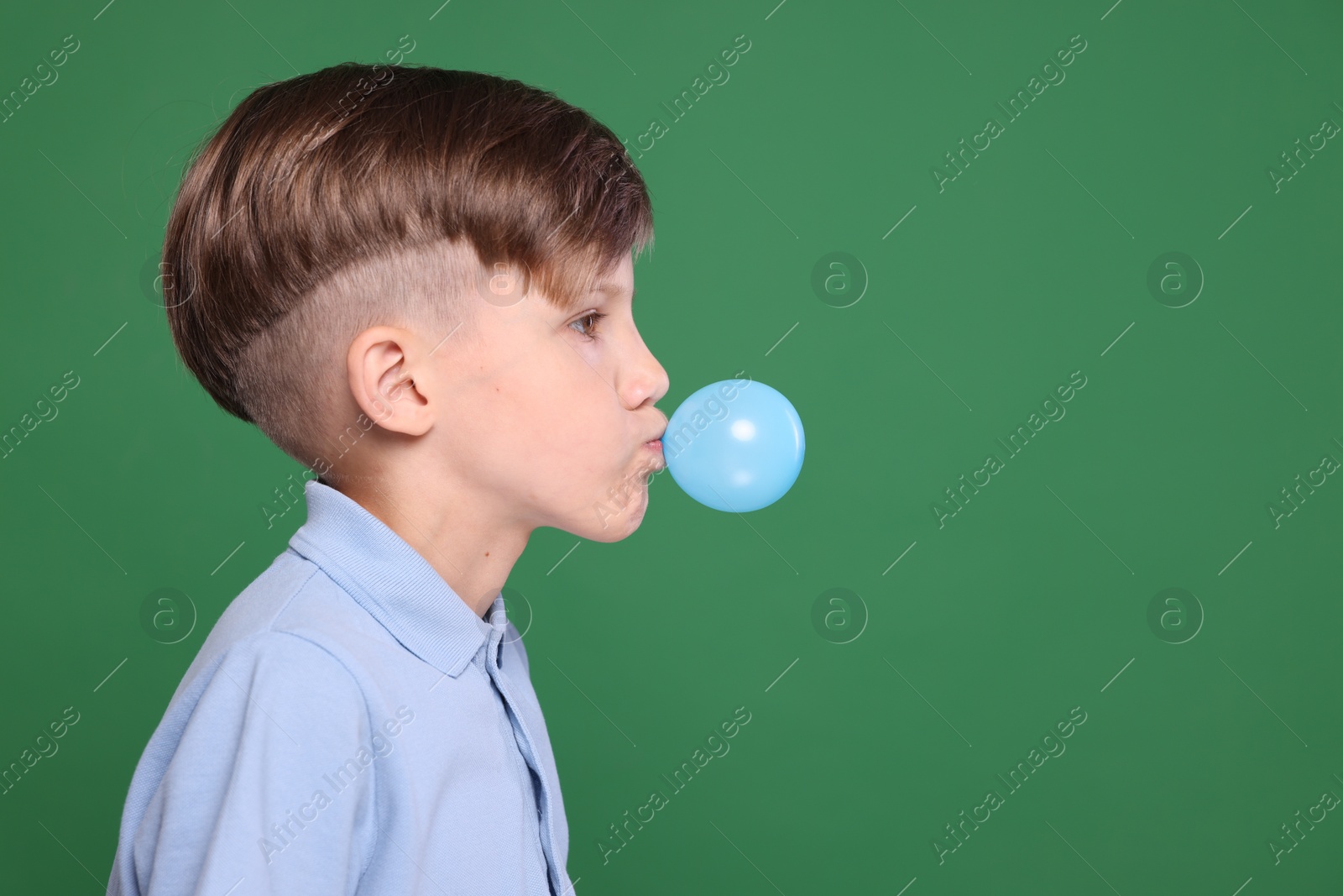 Photo of Boy blowing bubble gum on green background, space for text
