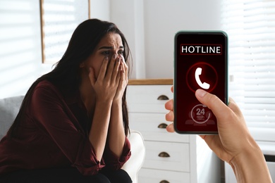 Image of Calling domestic violence hotline. Abused young woman crying indoors