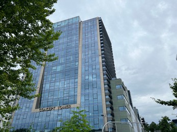 Photo of WARSAW, POLAND - JULY 13, 2022: Beautiful building and green trees against cloudy sky, low angle view