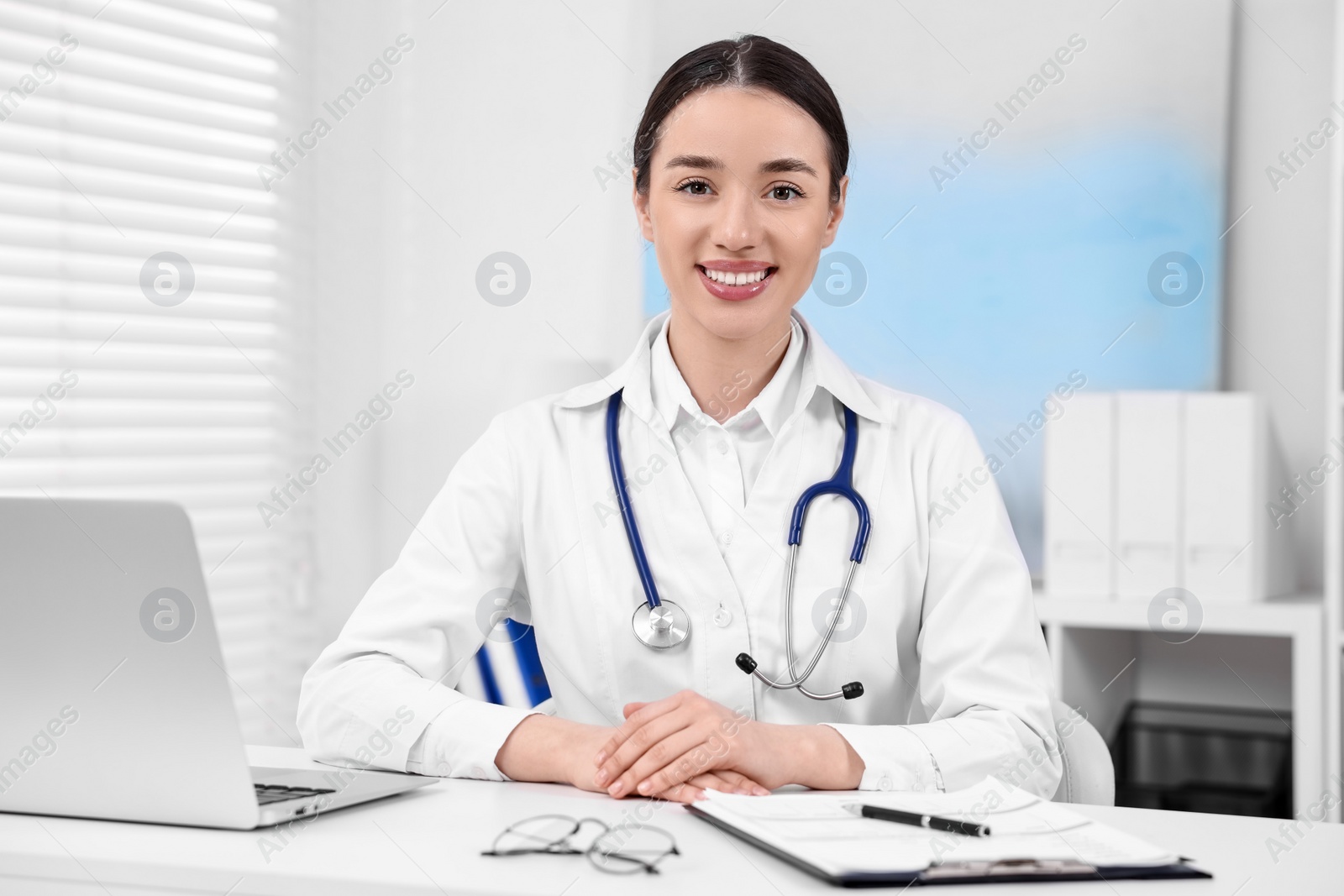 Photo of Medical consultant with stethoscope at table in clinic