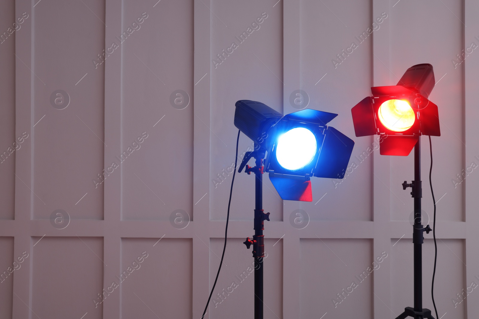 Photo of Bright red and blue spotlights near wall indoors, space for text