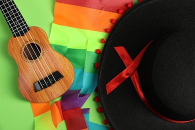 Black Flamenco hat and ukulele on green background, top view
