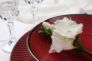 Photo of Dishes with flower and glasses on white table, closeup