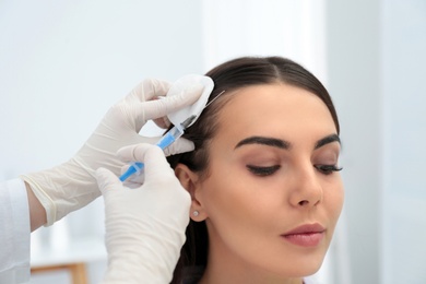 Photo of Young woman with hair loss problem receiving injection in salon