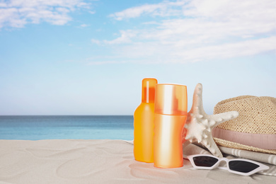 Image of Set of sun protection products and stylish accessories on sandy beach. Space for text