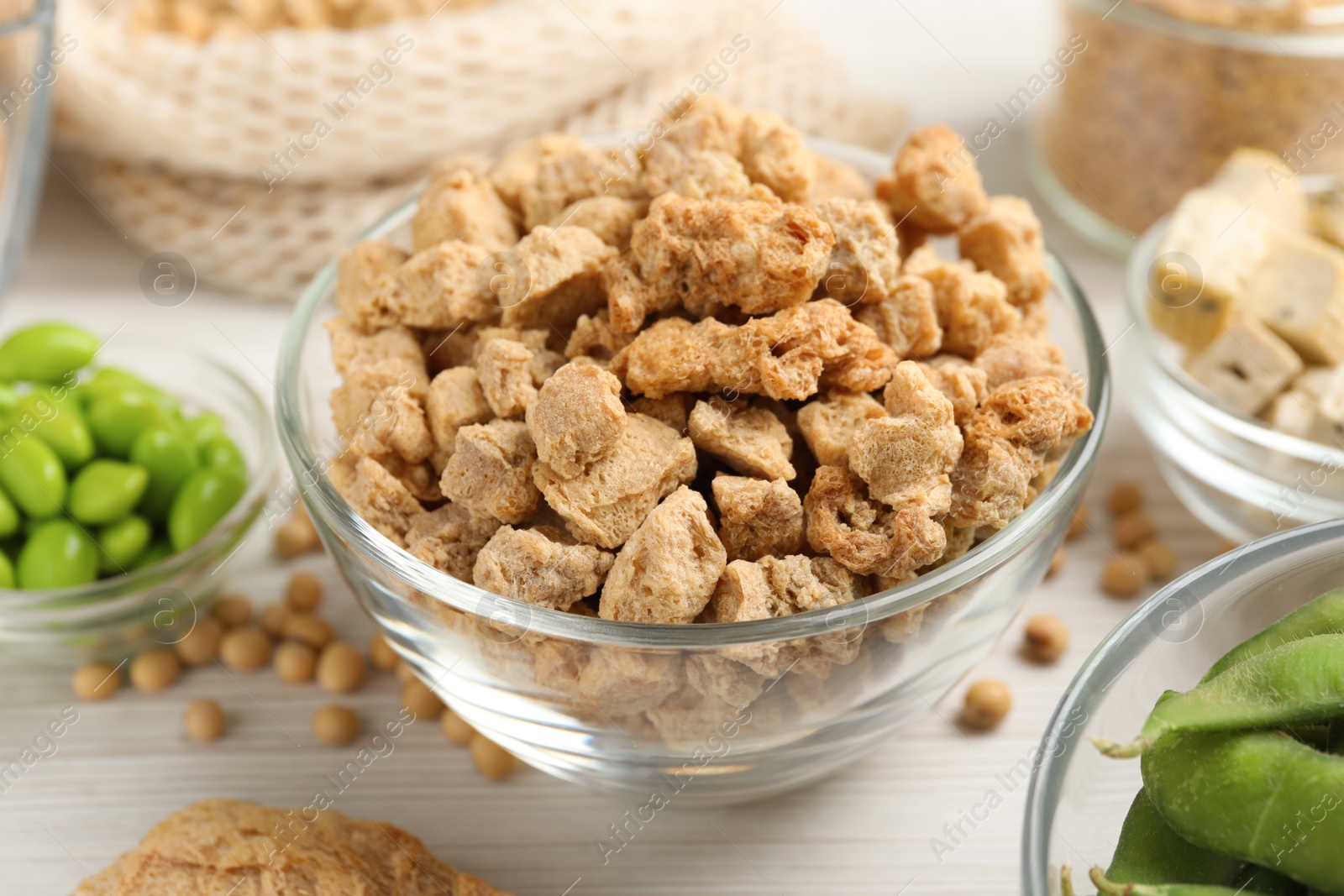 Photo of Dehydrated soy meat and other organic products on white wooden table, closeup