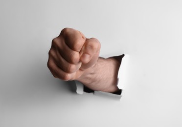 Photo of Man breaking through white paper with fist, closeup
