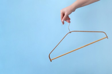 Photo of Woman holding hanger on light blue background, closeup. Space for text