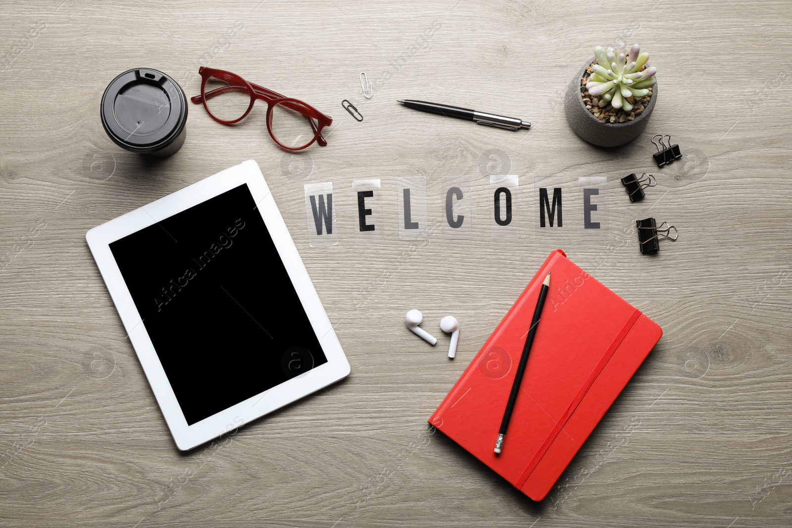 Photo of Flat lay composition with word Welcome, tablet and stationery on wooden table