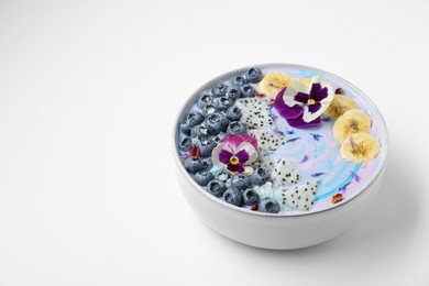 Delicious smoothie bowl with fresh fruits, blueberries and flowers on white background. Space for text