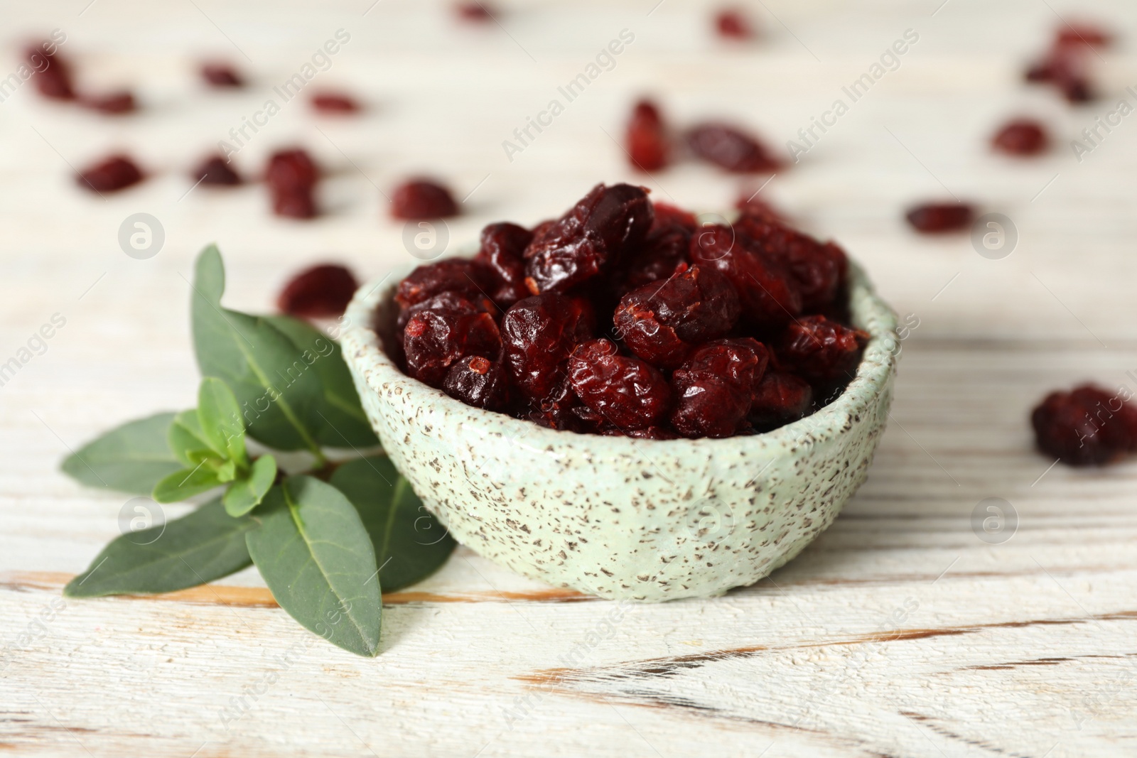 Photo of Tasty dried cranberries and leaves on white wooden table