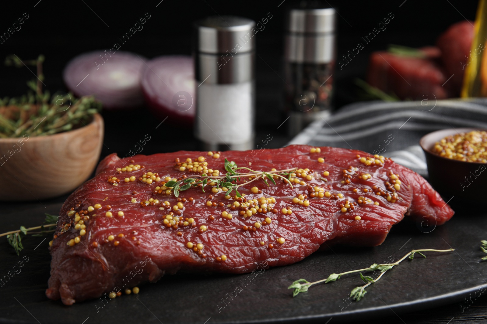 Photo of Fresh raw beef cut with thyme and mustard on table, closeup