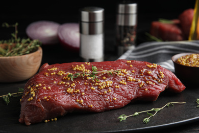 Photo of Fresh raw beef cut with thyme and mustard on table, closeup